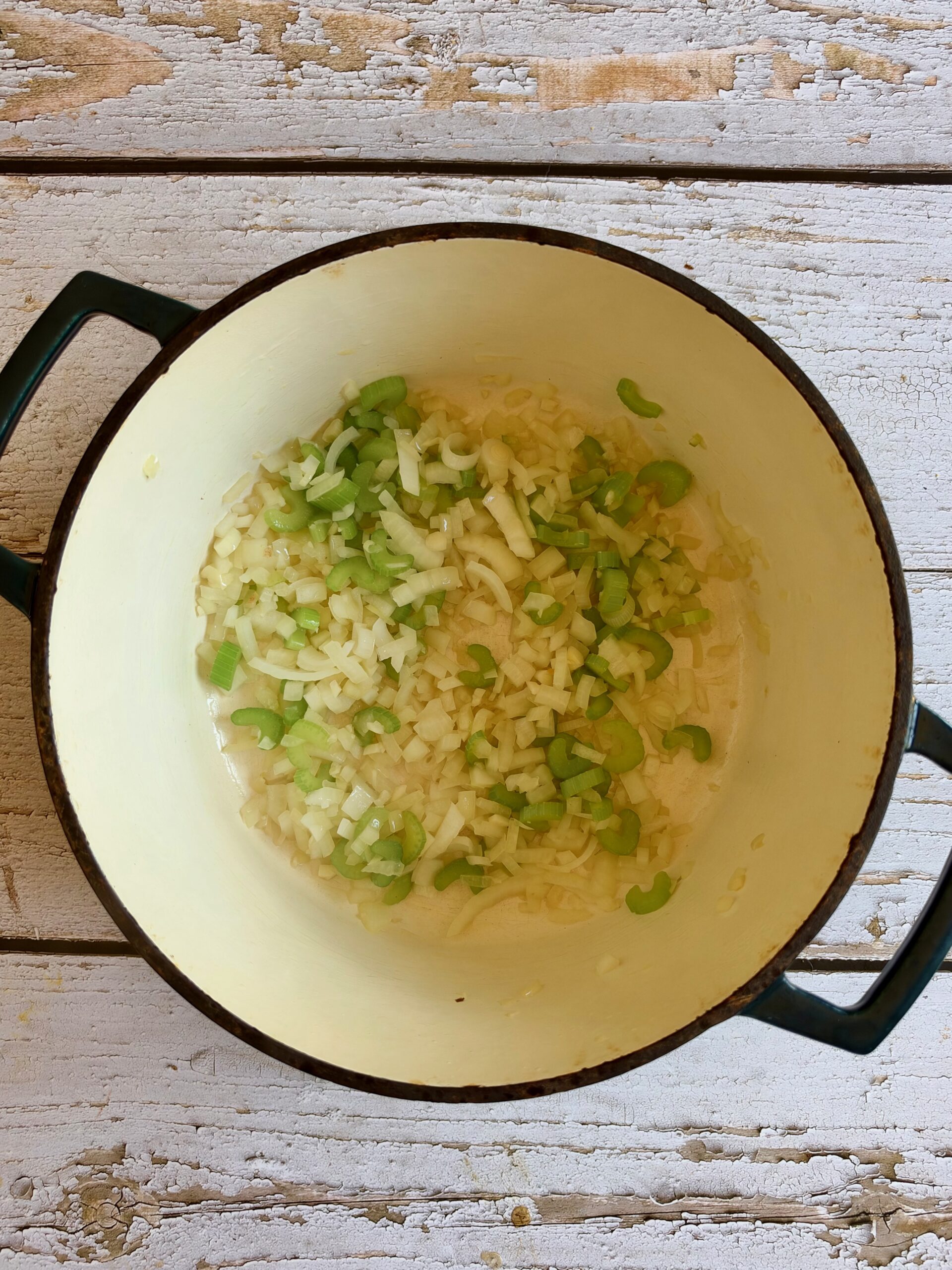 Diced onion and celery sautéing in a Dutch oven.