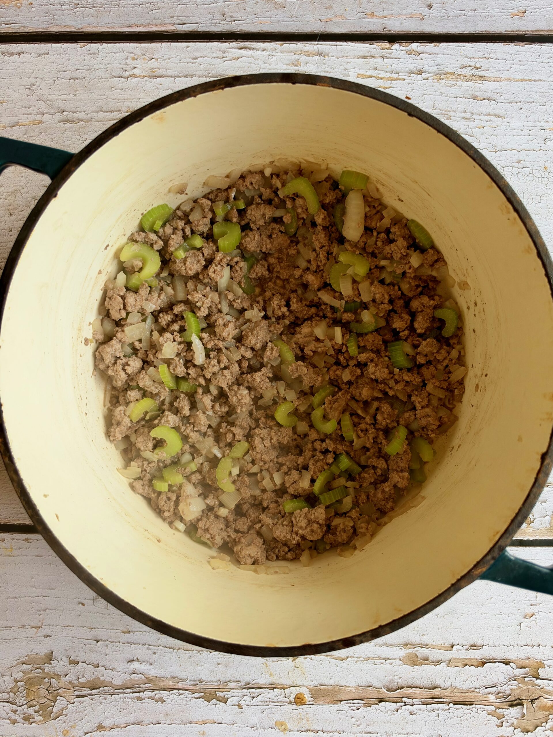 Browned ground beef with onion and celery in a Dutch oven.
