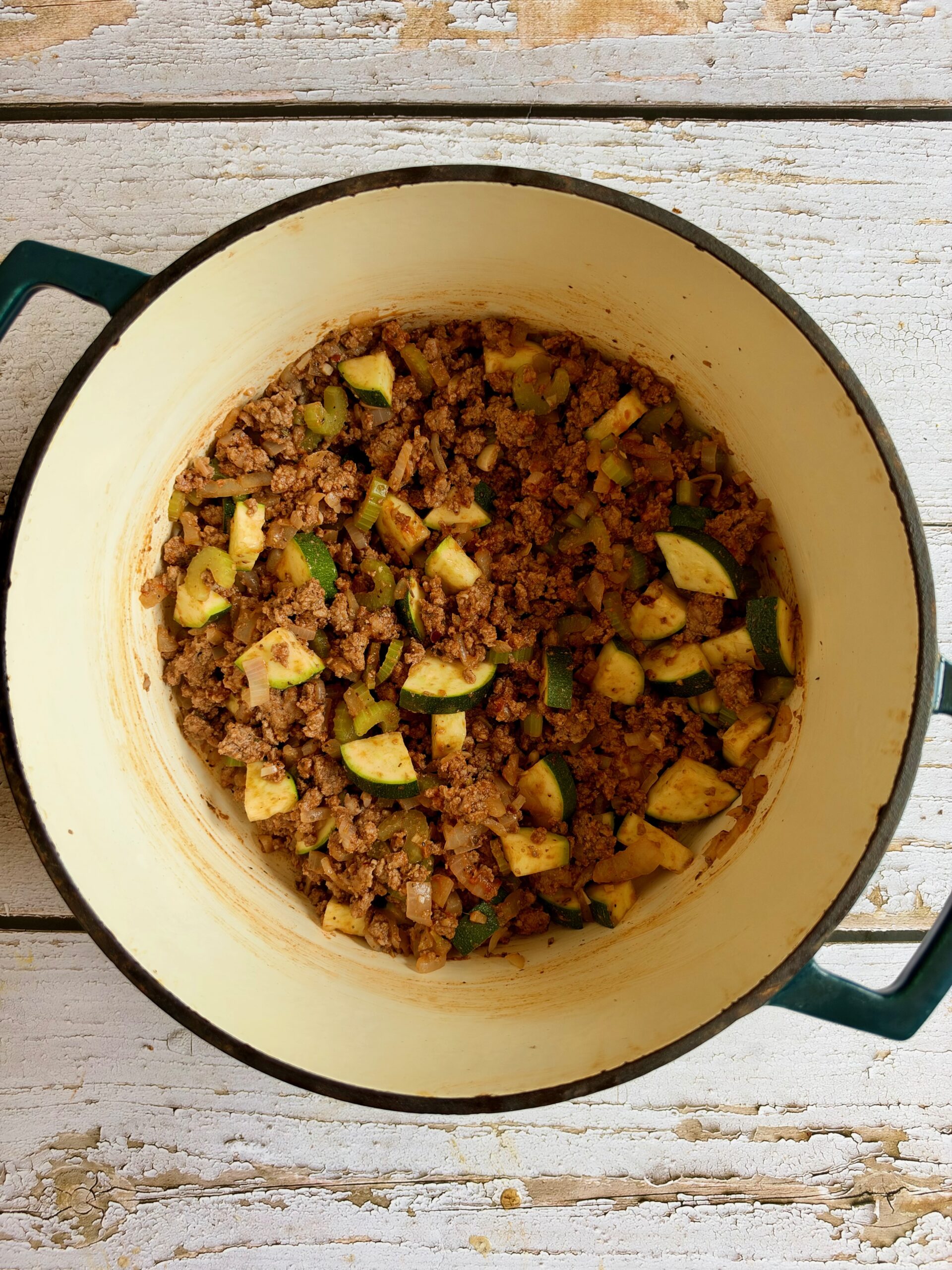 Diced zucchini, seasoning, and tomato paste stirred into ground beef in a Dutch oven.