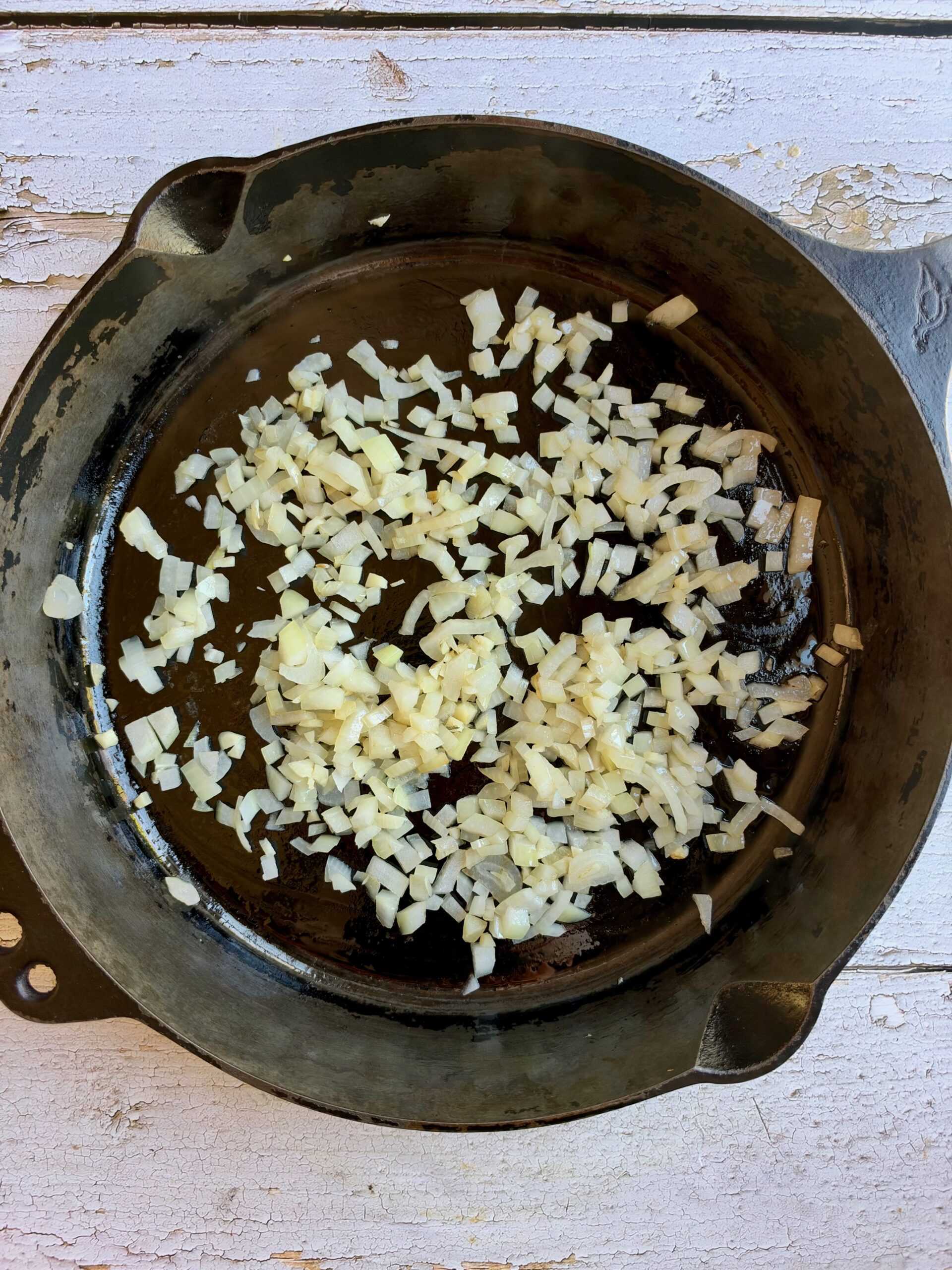 Diced onion and garlic sautéing in a cast iron skillet.