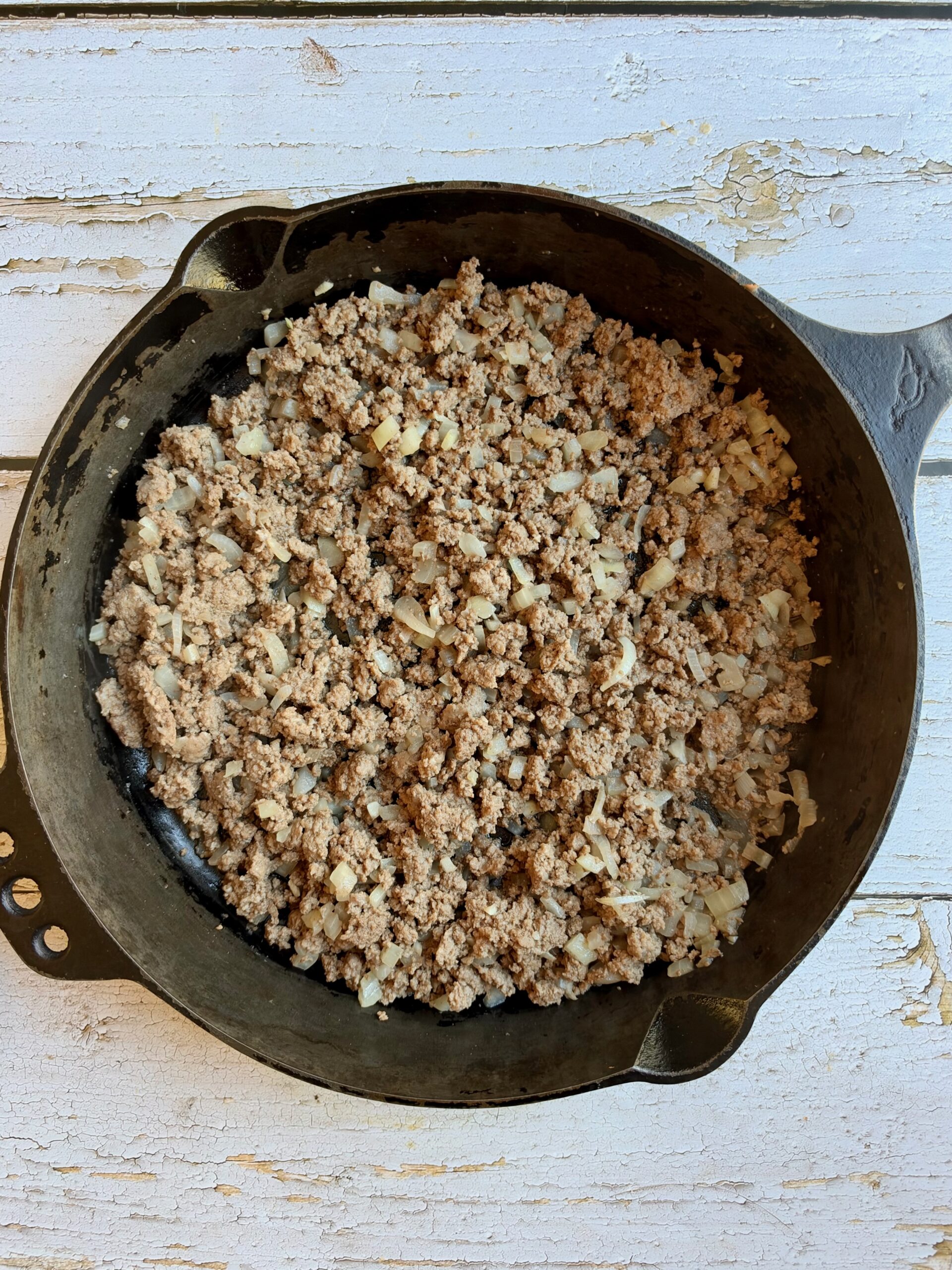 Browned ground beef with onion in a cast iron skillet.