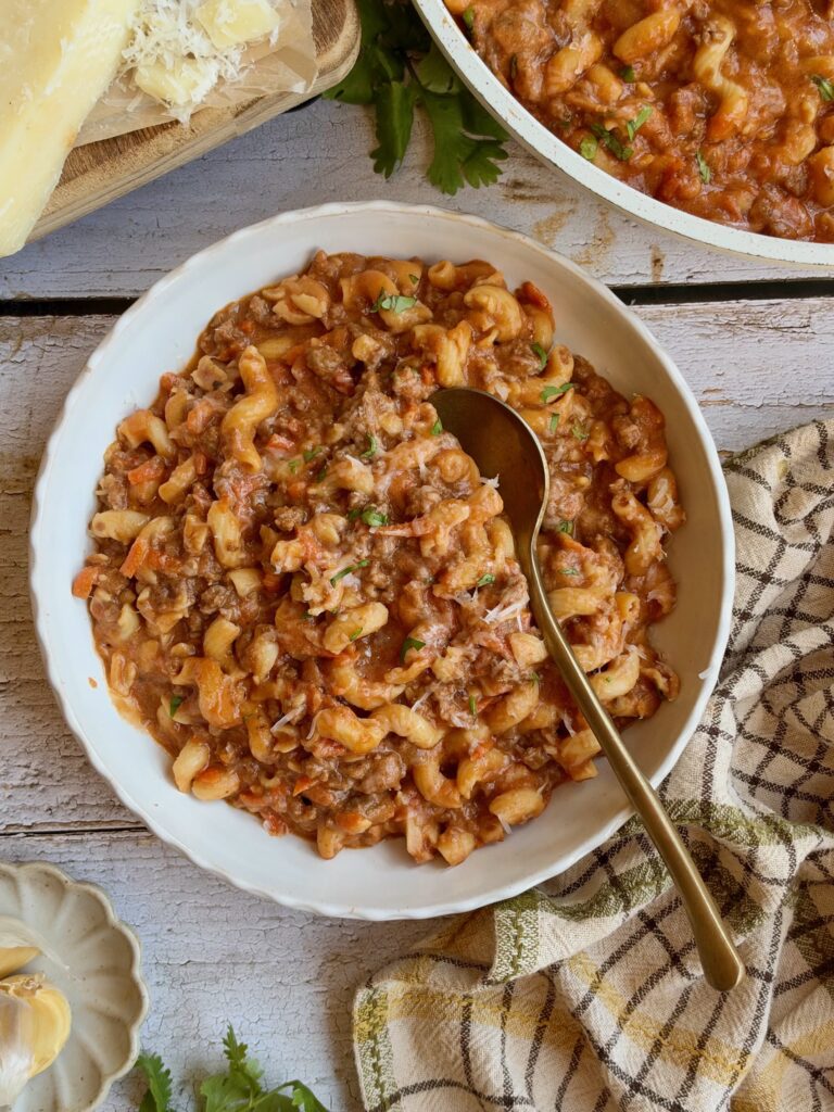 High protein cottage cheese pasta with ground beef in a white bowl with a gold spoon.
