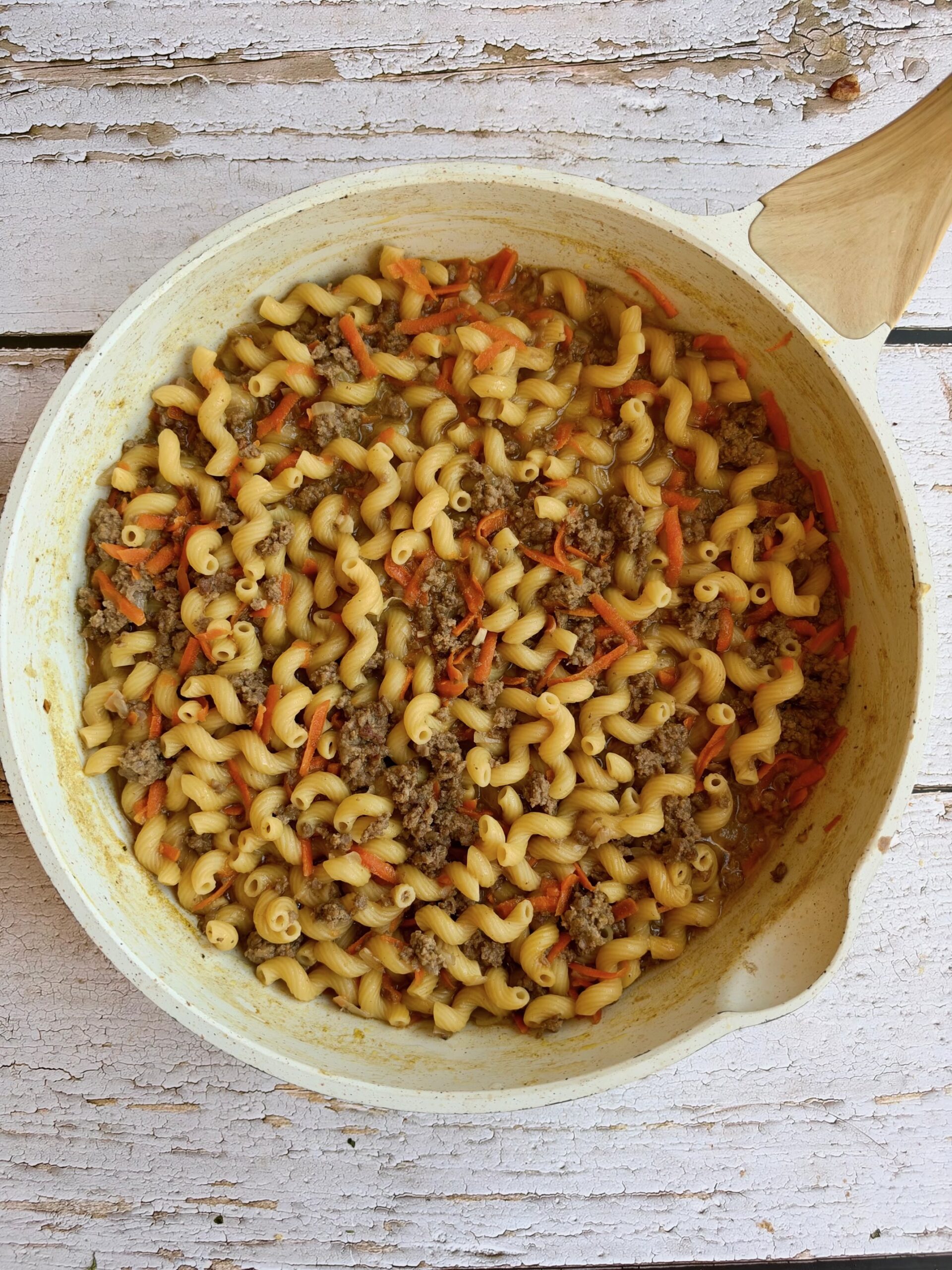 Cooked pasta with ground beef and carrots in a skillet after the broth has absorbed.
