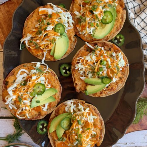 Buffalo chicken smash tacos topped with dill slaw, avocado, jalapeño, and buffalo sauce on a serving platter.