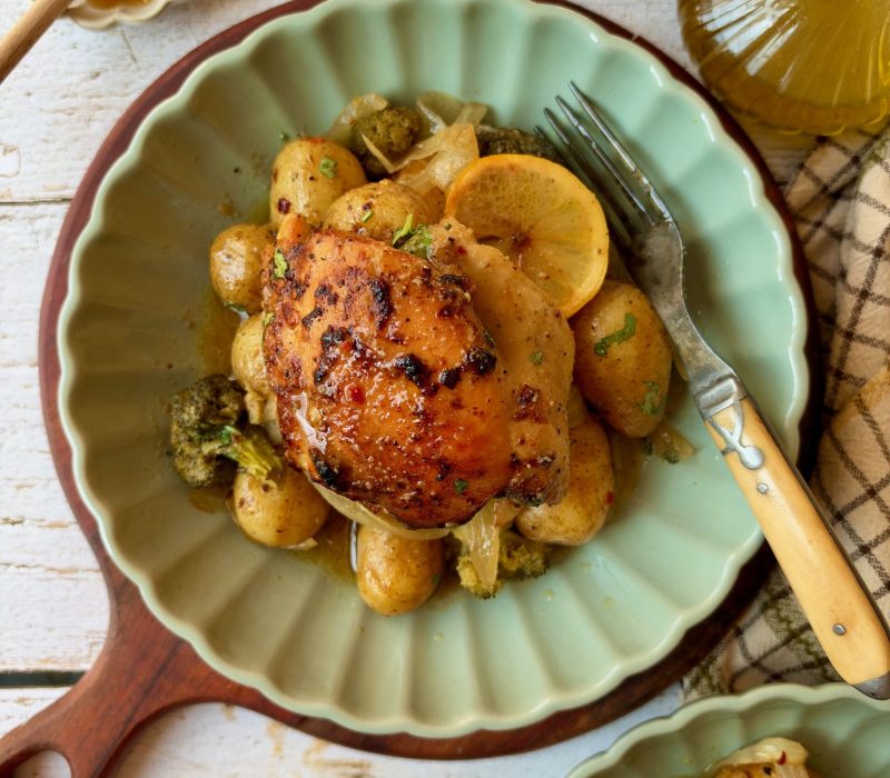 Dump and bake honey mustard chicken thigh served over potatoes and broccoli on a green plate with lemon slices.