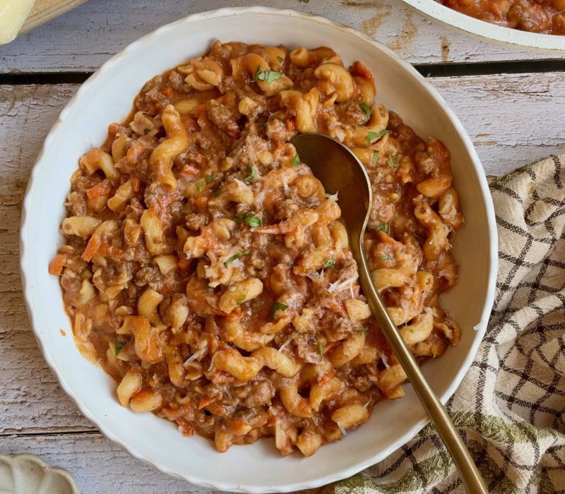 High protein cottage cheese pasta with ground beef in a white bowl with a gold spoon.